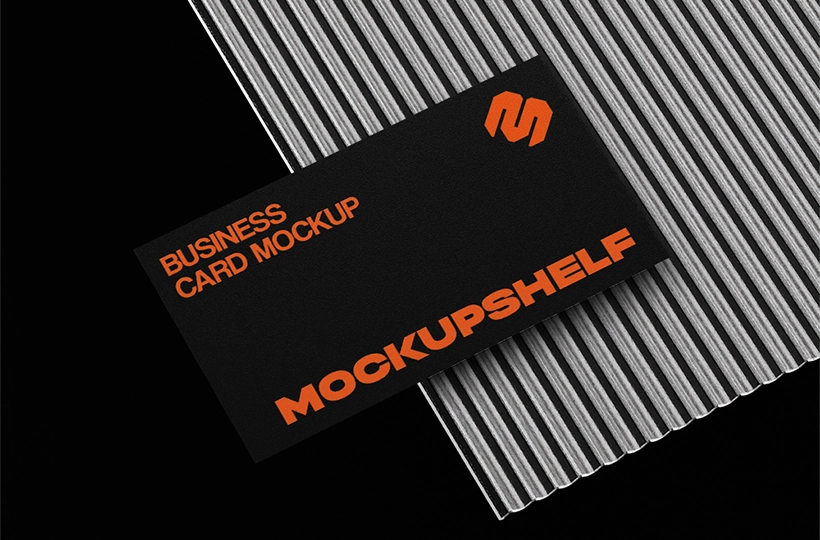 Black business card placed on a ribbed metallic surface with strong contrast