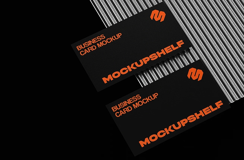 Two black business cards placed on a ribbed metallic surface with bold contrast