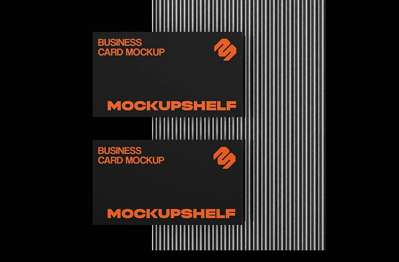 Two black business cards placed side by side on a ribbed metallic surface with bold contrast