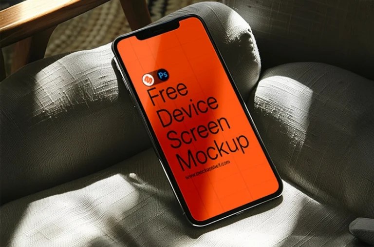 Free phone screen mockup PSD — black smartphone lying on sunlit linen sofa in warm living room