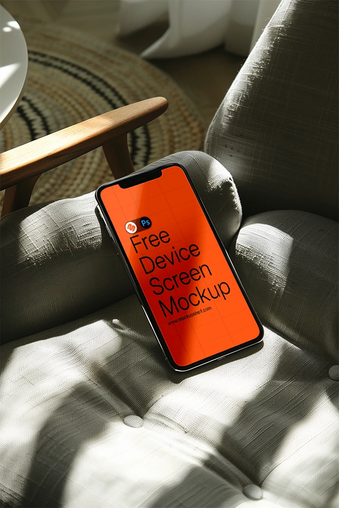Free iPhone Mockup with Design on a Chair – Top Angled PSD Template | MockupShelf Free iPhone Mockup with design on a chair – top angled smartphone on soft gray fabric under natural daylight | MockupShelf