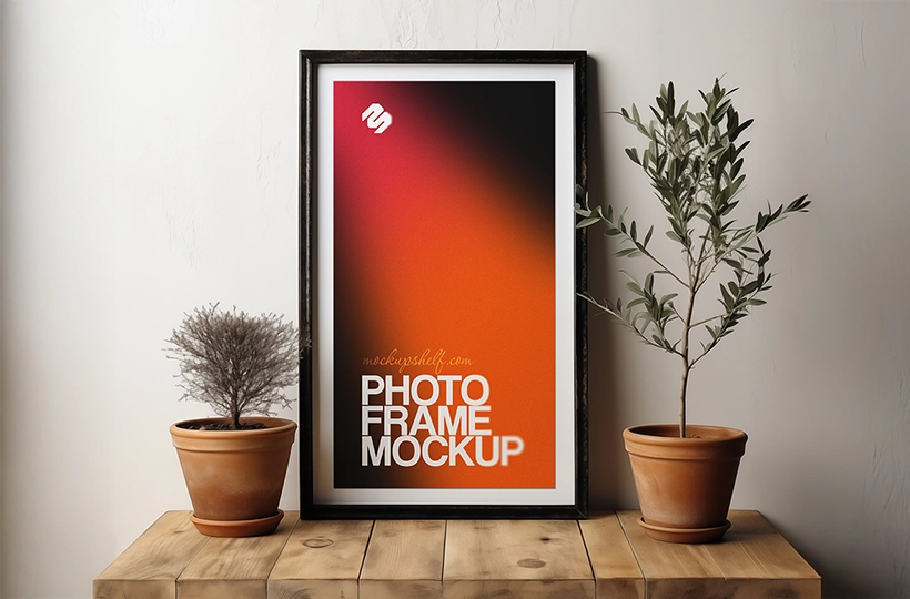 Framed photo mockup displayed on a wooden table with two potted plants